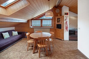 Una stanza accogliente con soffitto in legno, un tavolo rotondo in legno e un divano dai toni scuri.