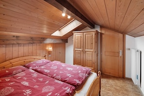 A wooden-paneled room with a bed, a wardrobe, and a skylight.