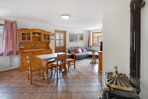 A cozy living room with a wooden dining table, chairs, a sofa, and a fireplace. - Apartment 'Doleda' with Mountain View, Wi-Fi and Air Conditioning (Soraga)