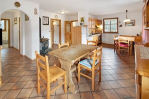 A kitchen with wooden cabinets, a dining table, chairs, and a tiled floor.