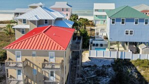 A beachfront property with multiple buildings, including a two-story house with a red roof and a white building with a green roof. - Affordable gulfside townhome (Port Saint Joe)