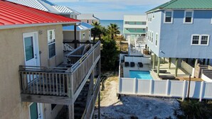 A beachfront property with a pool, multiple buildings, and a wooden deck. - Affordable gulfside townhome (Port Saint Joe)