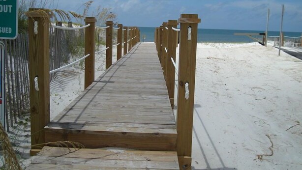 A wooden boardwalk leading to a sandy beach with a clear blue sky. - Affordable gulfside townhome (Port Saint Joe)