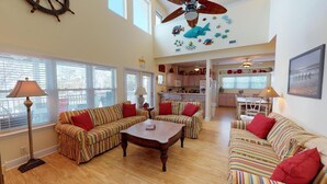 A spacious living room with striped sofas, a coffee table, and a ceiling fan.