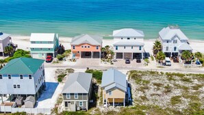 A coastal residential area with houses, some with attached garages, and a beach in the background.