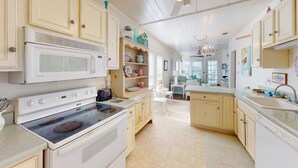 A kitchen with white appliances, wooden cabinets, and a chandelier.