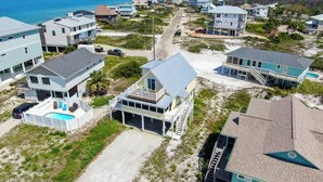 Uma área residencial à beira-mar, com casas que possuem varandas, uma piscina e vista clara para o oceano.