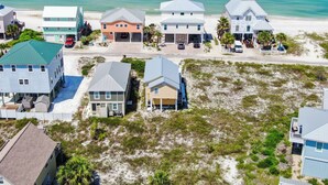 A coastal residential area with houses on stilts, a beach, and clear blue waters. - Gulf View Beach Cottage across from beach access (Port Saint Joe)