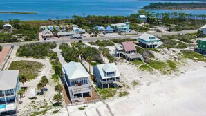 An aerial view of a coastal area with multiple buildings, including a large resort with multiple structures and a beach in the foreground. - Oceanfront-New furnishing-Steps to Beach (Port Saint Joe)