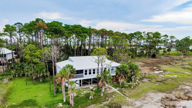 A large house surrounded by a dense forest and a sandy beach area. - Bayfront Home near Salinas Park and Pickleball (Port Saint Joe)