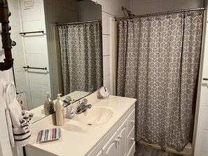 Un baño con lavamanos blanco, espejo y cortina de ducha con diseño geométrico.