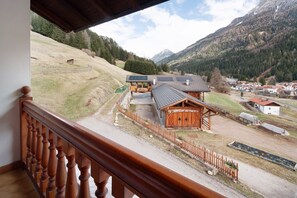 Een houten chalet met een metalen dak, omringd door een houten hek, gelegen voor een bergachtig landschap.
