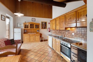 Une cuisine avec des meubles de rangement en bois, un pare-feu en carrelage, une cuisinière et un évier.