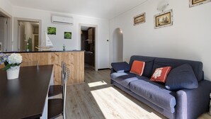 Un espacio habitable moderno con comedor, sofá y cocina al fondo.