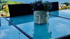 Una mesa de vidrio con una planta en maceta y vista al mar.
