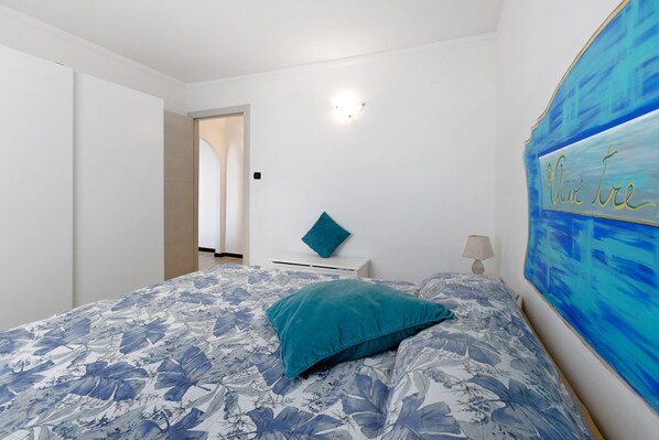 Un dormitorio con una cama, una mesita de noche, una lámpara y un cuadro en la pared.