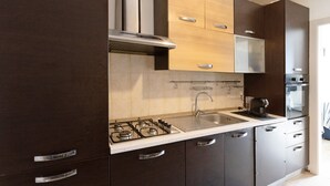 Una cocina moderna con armarios oscuros, una campana de acero inoxidable, un lavamanos doble y un horno empotrado.