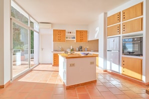 Eine moderne Küche mit Kochinsel, eingebauten Holzsäcken und einem großen Fenster.