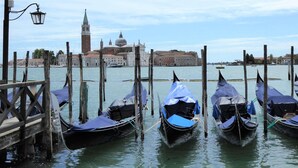 Gondolas docked at a pier with a historic building in the background. - Belvilla by OYO Appartamento Nero (Jesolo)