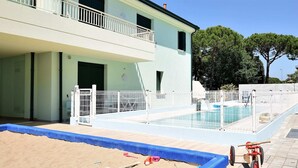 A swimming pool with a sandy area and a small wooden boat. - Belvilla by OYO Appartamento Nero (Jesolo)