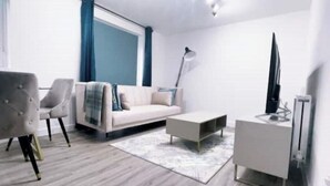 A modern living room with a sofa, a coffee table, a TV, and a lamp.