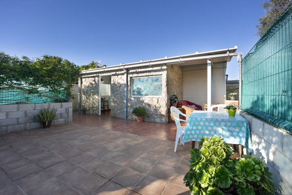A patio area with a table and chairs, potted plants, and a stone wall.