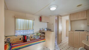 Een ruimtelijk ingerichte camper met een bed, een kitchenette en opbergkasten.