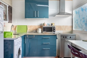 A compact kitchen with a washing machine, a microwave, and a stove.