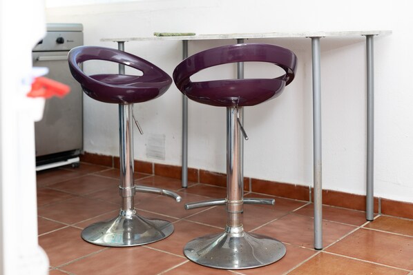 Two purple bar stools with metal bases and a white table.