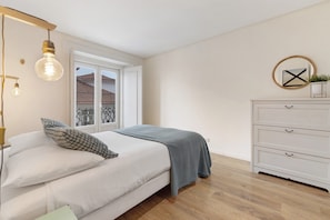 Ein Schlafzimmer mit Bett, Nachttischlampen, einem Schminktisch und einem Fenster mit Aussicht.