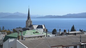 A coastal town with a prominent church spire, a body of water, and distant mountains. - Terrazas del lago I U with a view of Nahuel Huapi Lake (San Carlos de Bariloche)