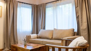 Een gezellige woonkamer met een houten plafond, een bank, een houten bijzettafeltje en een stoel.