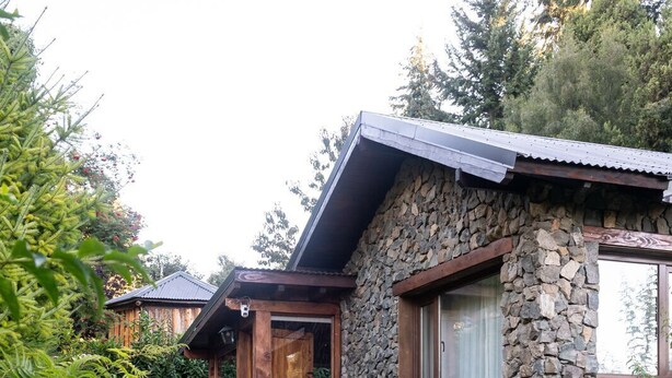 Een stenen huis met een houten deur en raam, omringd door een gazon en een pad van stenen.