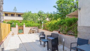 A patio with outdoor furniture, a wooden fence, and a view of a building with a balcony.