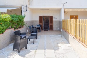 An outdoor patio with wicker furniture, a tiled floor, and a wooden fence.
