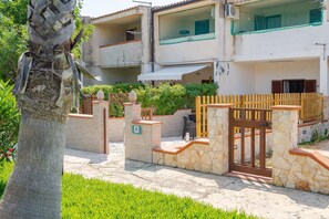 A multi-story building with a stone facade, a gated entrance, and a small outdoor seating area.