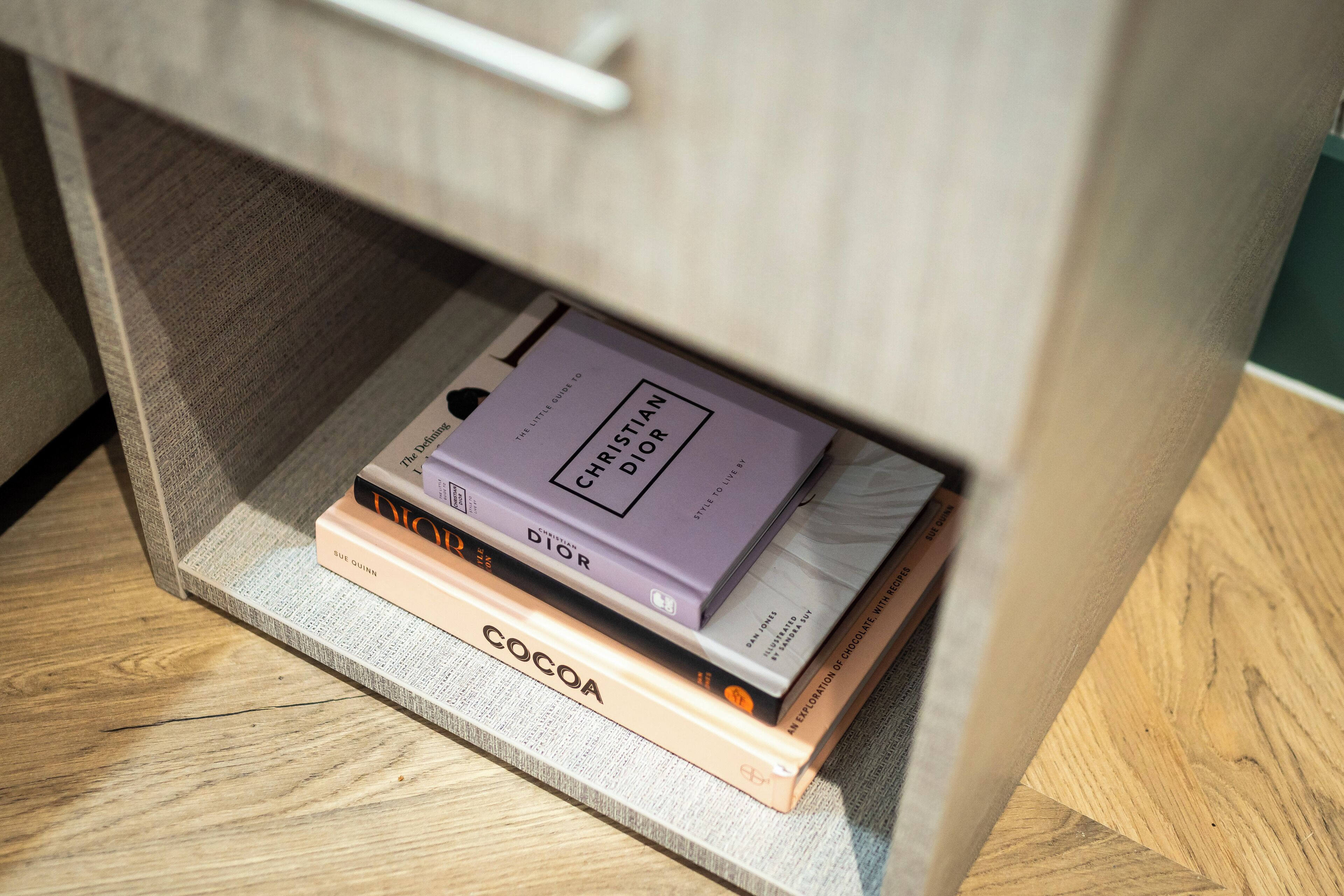 A stack of books under a wooden desk.