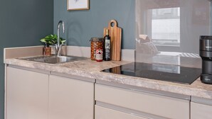 Una cocina moderna con una campana de acero inoxidable, un lavamanos y una encimera con una planta y un tarro de mermelada.