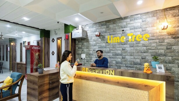 A reception desk with a 'Limetree' sign, a Coca-Cola fridge, and a receptionist. - Lime Tree Hotel and Banquet Vrindavan (Mathura)