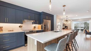 Una cocina moderna con armarios oscuros, electrodomésticos de acero inoxidable y una isla grande con taburetes de bar.