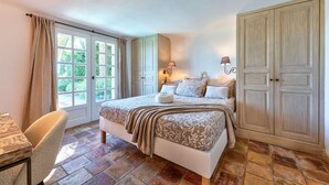 Une chambre à coucher avec un lit, une chaise, une armoire et une fenêtre avec des rideaux.