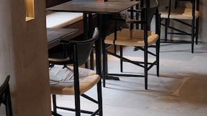 En restaurantindretning med stenvægge, træborde og sorte stole.