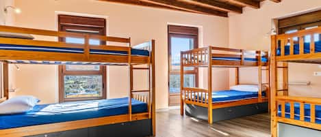 A room with bunk beds, wooden flooring, and a sloped ceiling.