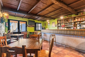A restaurant interior with wooden tables and chairs, a bar area, and a tiled floor. - Room 'Habitacion 3' with Mountain View, Wi-Fi and Air Conditioning (Asturias)