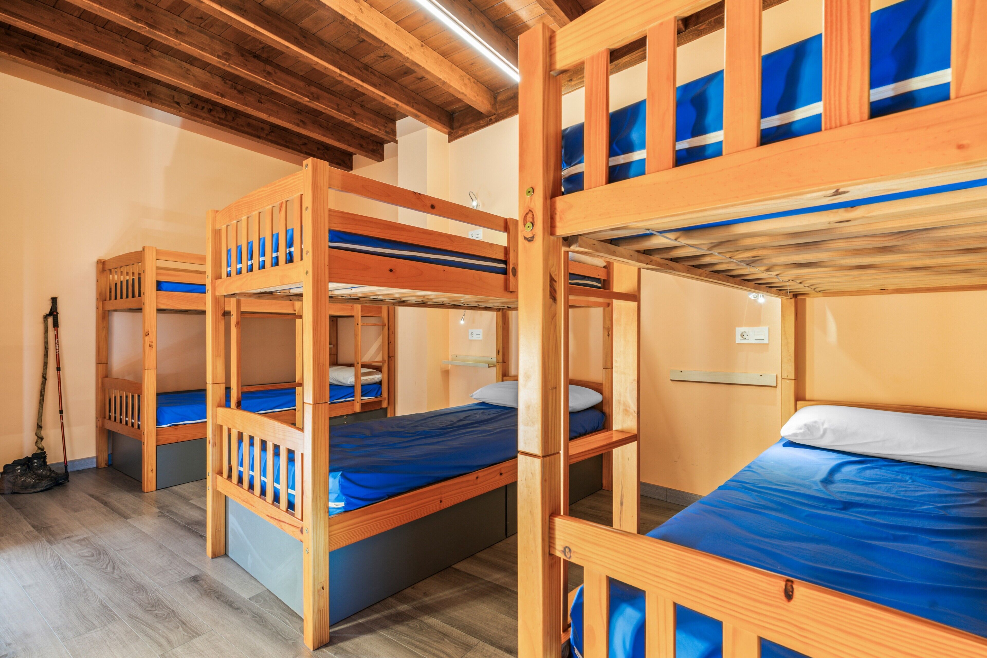 Una habitación con literas, vigas de madera en el techo y suelo de madera.