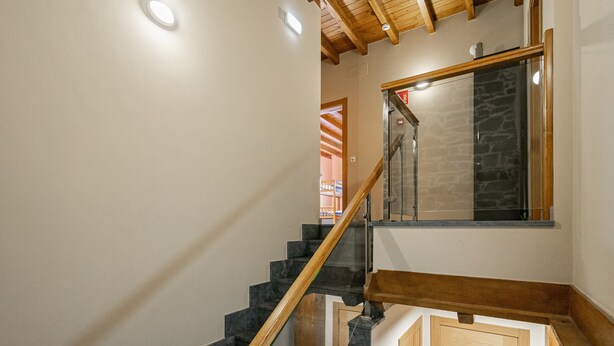 A staircase with wooden handrails and black steps, leading to a room with a stone wall and a window. - Room 'Habitacion 3' with Mountain View, Wi-Fi and Air Conditioning (Asturias)