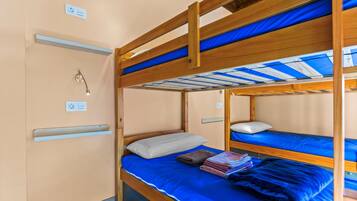 Habitación con literas de madera, colchón azul y almohada blanca.