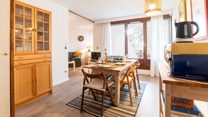 Un espace repas comprenant une table en bois, des chaises et un luminaire suspendu.