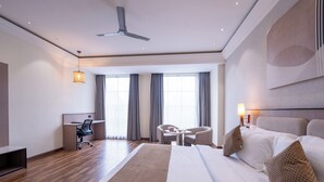 A modern hotel room with a large bed, a desk, a chair, and a small table. - Ramee ColleXtion Amritsar, Near Golden Temple (Amritsar)