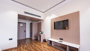 A modern hotel lobby with a wooden floor, a bench, a TV mounted on a wooden panel wall, and a small desk with a trash can. - Ramee ColleXtion Amritsar, Near Golden Temple (Amritsar)